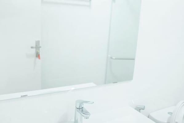 Un baño con espejo, lavamanos e inodoro.