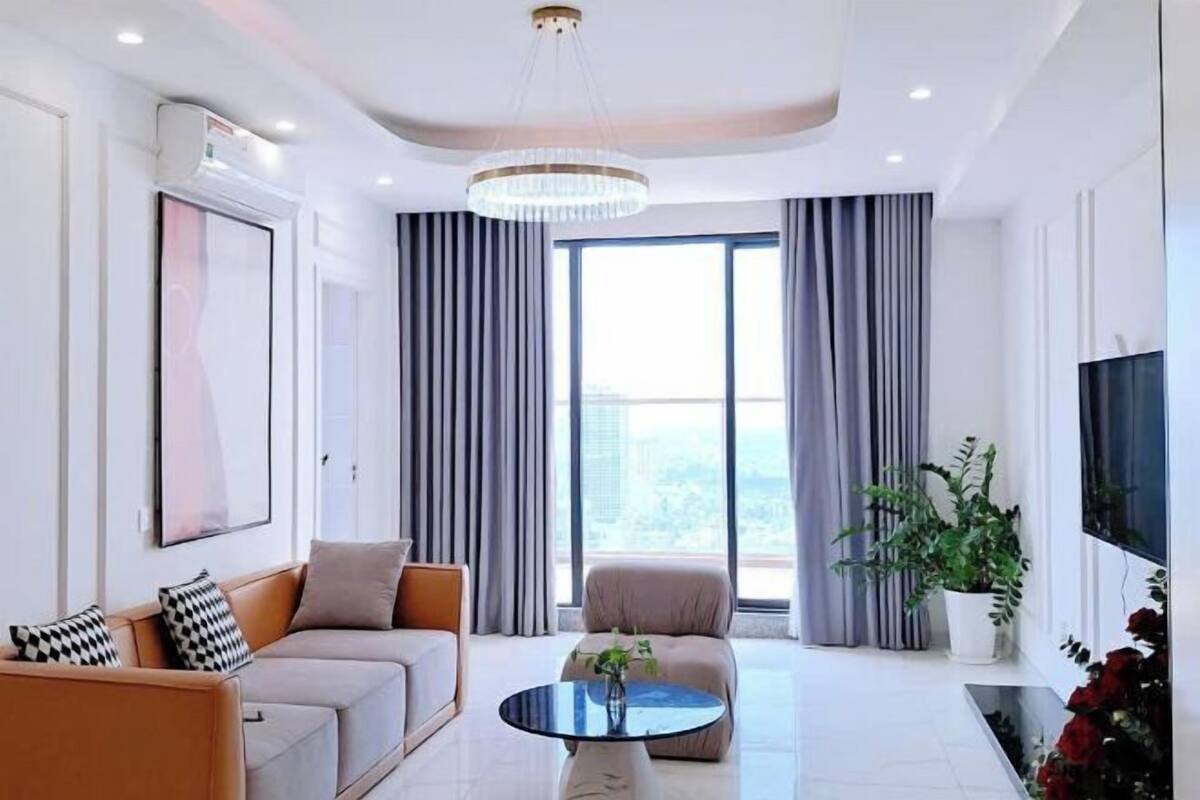 A modern living room with a sofa, armchair, round coffee table, and a large window with curtains.