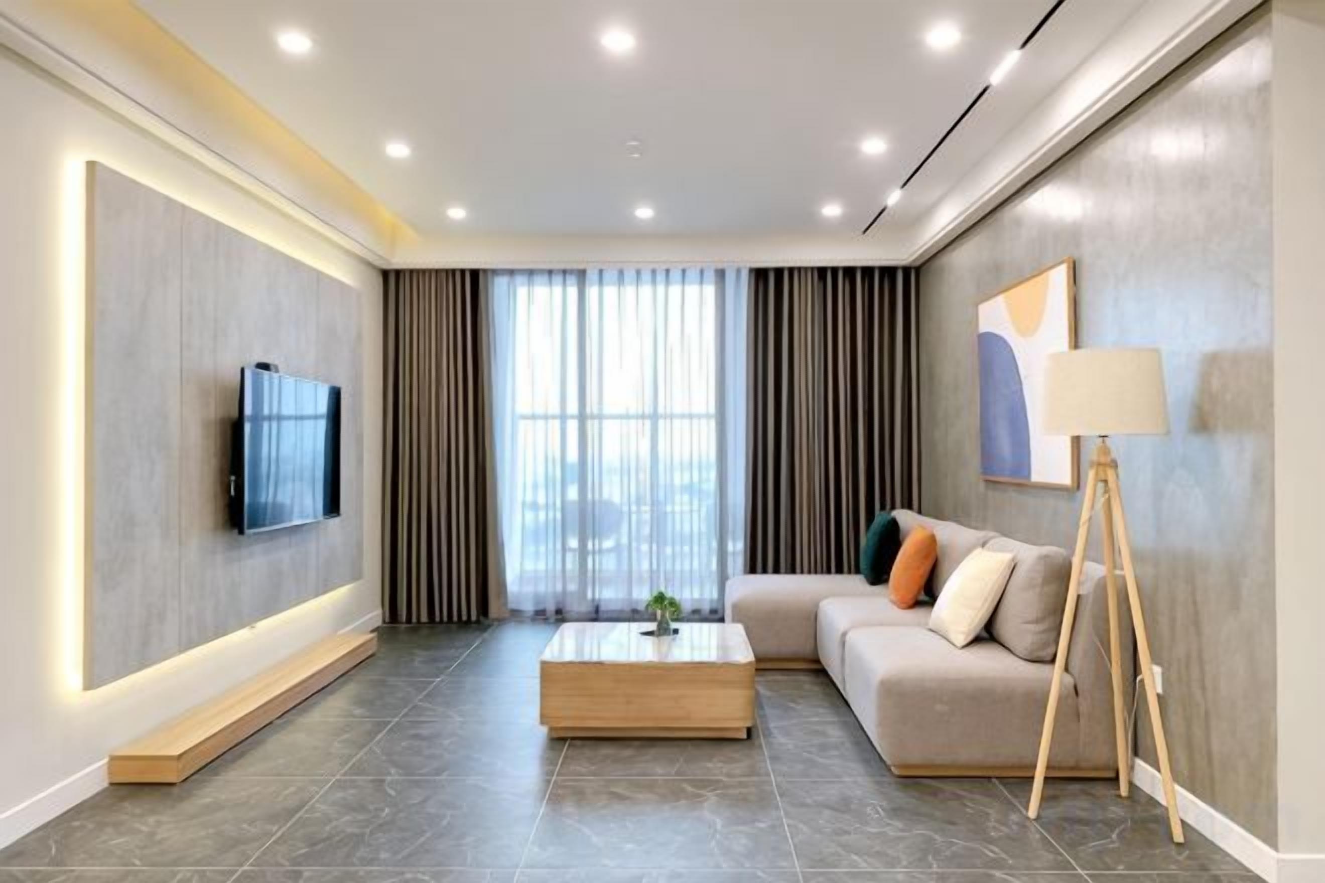 A modern living room with a flat-screen TV, a sofa, a coffee table, and a floor lamp.