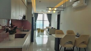 A modern kitchen with a central island, a dining area with chairs, and a living space with a sofa. - TSQ STAY Hotel Apartment (Hanoi)