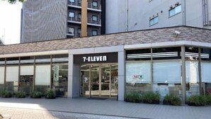 A 7-Eleven store with a modern facade, large glass windows, and a tiled pavement area. - Baden² MINPAKU STYLE～ART～HONMACHI 1 bedroom, accommodates up to 3 people (Osaka)
