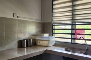 A kitchen with a sink, a window with blinds, and a countertop with a white container and a metal pitcher. - LestariHome2, KLIA Sepang (Sepang)