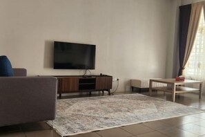 A living room with a flat-screen TV mounted on the wall, a sofa, a coffee table, and a patterned rug. - LestariHome2, KLIA Sepang (Sepang)
