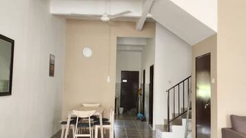 Un grand espace de vie comprenant une table et des chaises, un escalier et une porte donnant sur une autre pièce.