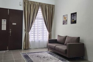 A room with a brown door, a window with curtains, a brown sofa, and a patterned rug. - LestariHome2, KLIA Sepang (Sepang)
