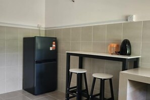 A kitchen with a black refrigerator, a white table with two stools, and a coffee machine. - LestariHome2, KLIA Sepang (Sepang)