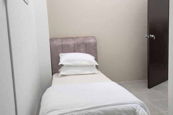 A small, single-bed room with a headboard, a door, and a tiled floor. - LestariHome2, KLIA Sepang (Sepang)
