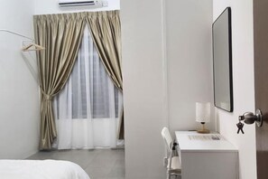 A hotel room with a bed, a desk with a lamp, and a window with curtains. - LestariHome2, KLIA Sepang (Sepang)