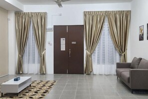 A room with a sofa, a coffee table, curtains, a door, and a patterned rug. - LestariHome2, KLIA Sepang (Sepang)
