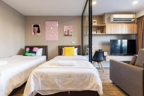 Habitación de hotel con dos camas, un sofá, un televisor y un aire acondicionado.