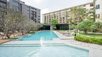 A swimming pool surrounded by greenery and modern buildings.