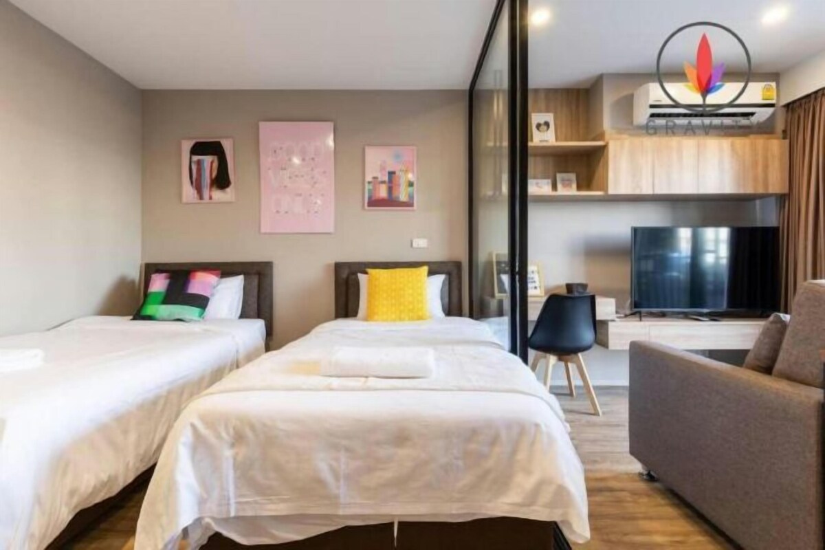 Une chambre d’hôtel avec deux lits, un canapé, une télévision et une kitchenette.