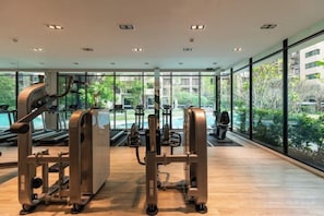 Une salle de sport équipée de machines de cardio, de poids libres et d’un tapis de course.