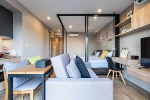 Un interior moderno con un sofá, una mesa de comedor, sillas, una cama y un televisor.