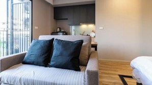 A modern room with a bed, a window, a kitchenette, and a view of the outside.