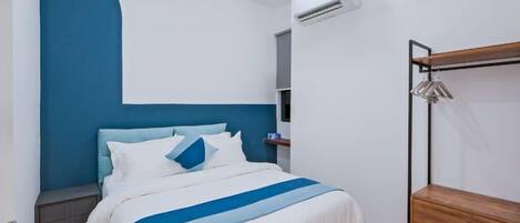 A bedroom with a bed, a wooden dresser, a ceiling fan, and an air conditioning unit.