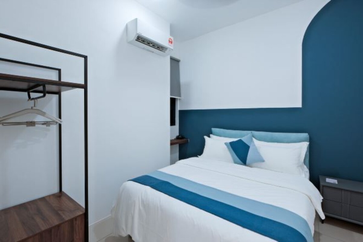 A modern hotel room with a bed, a wardrobe, a hanging rack, and an air conditioning unit.