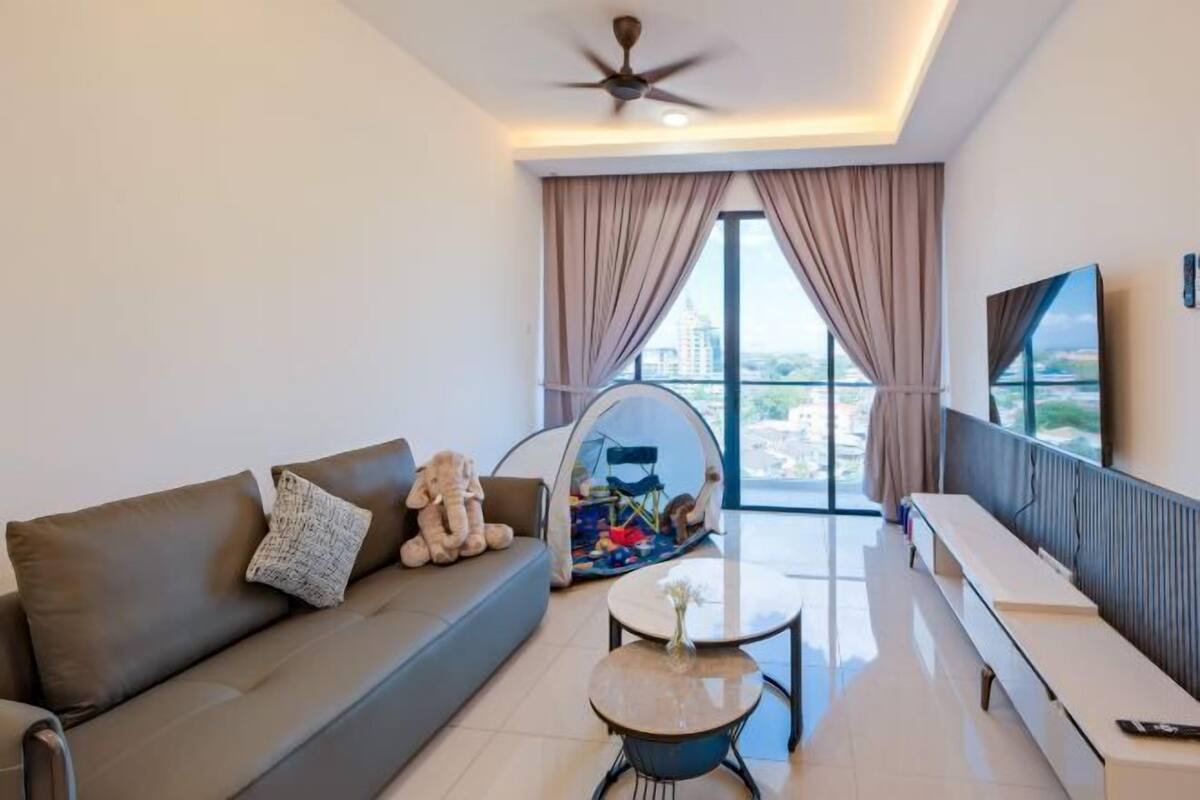 A modern living room with a sofa, a round coffee table, a hanging chair, and a large window with curtains.