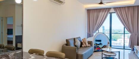 A modern living room with a dining area, a sofa, a ceiling fan, and a large window with curtains.