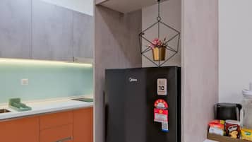 A modern kitchen with a black refrigerator, a hanging light fixture, and a countertop with various items.