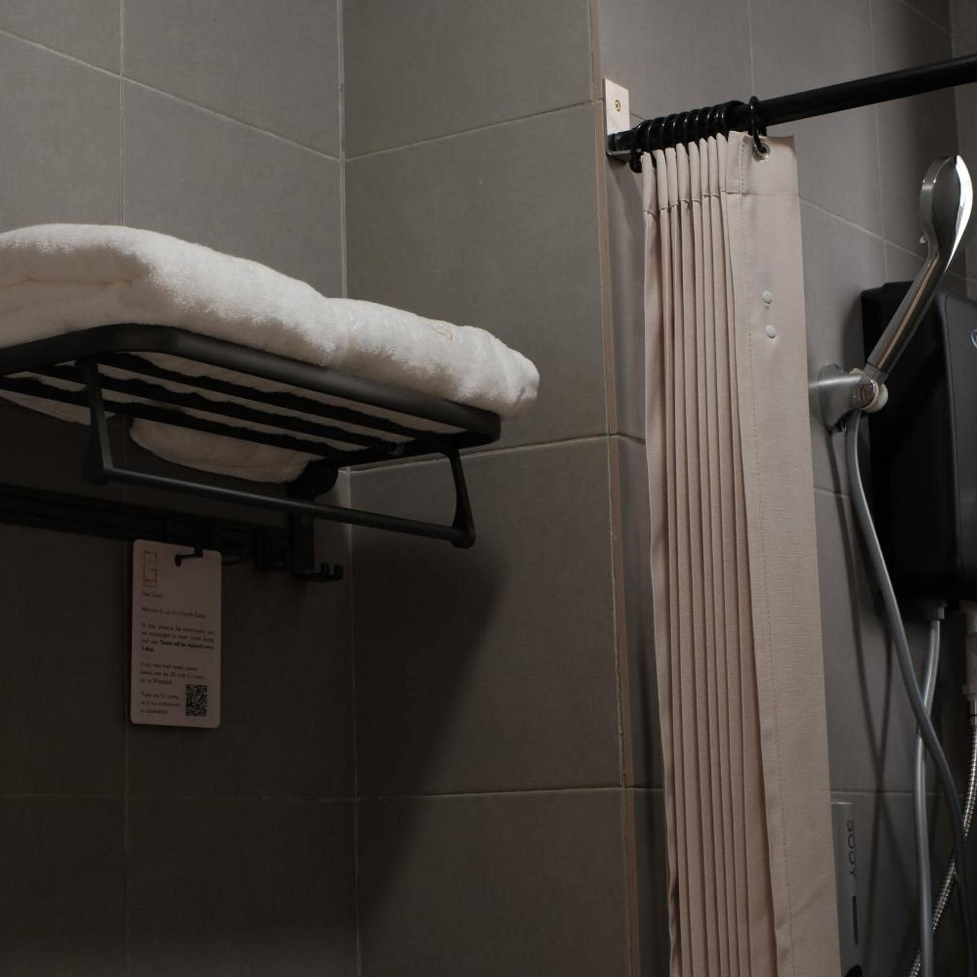 A bathroom with a towel rack, a shower curtain, and a handheld showerhead.