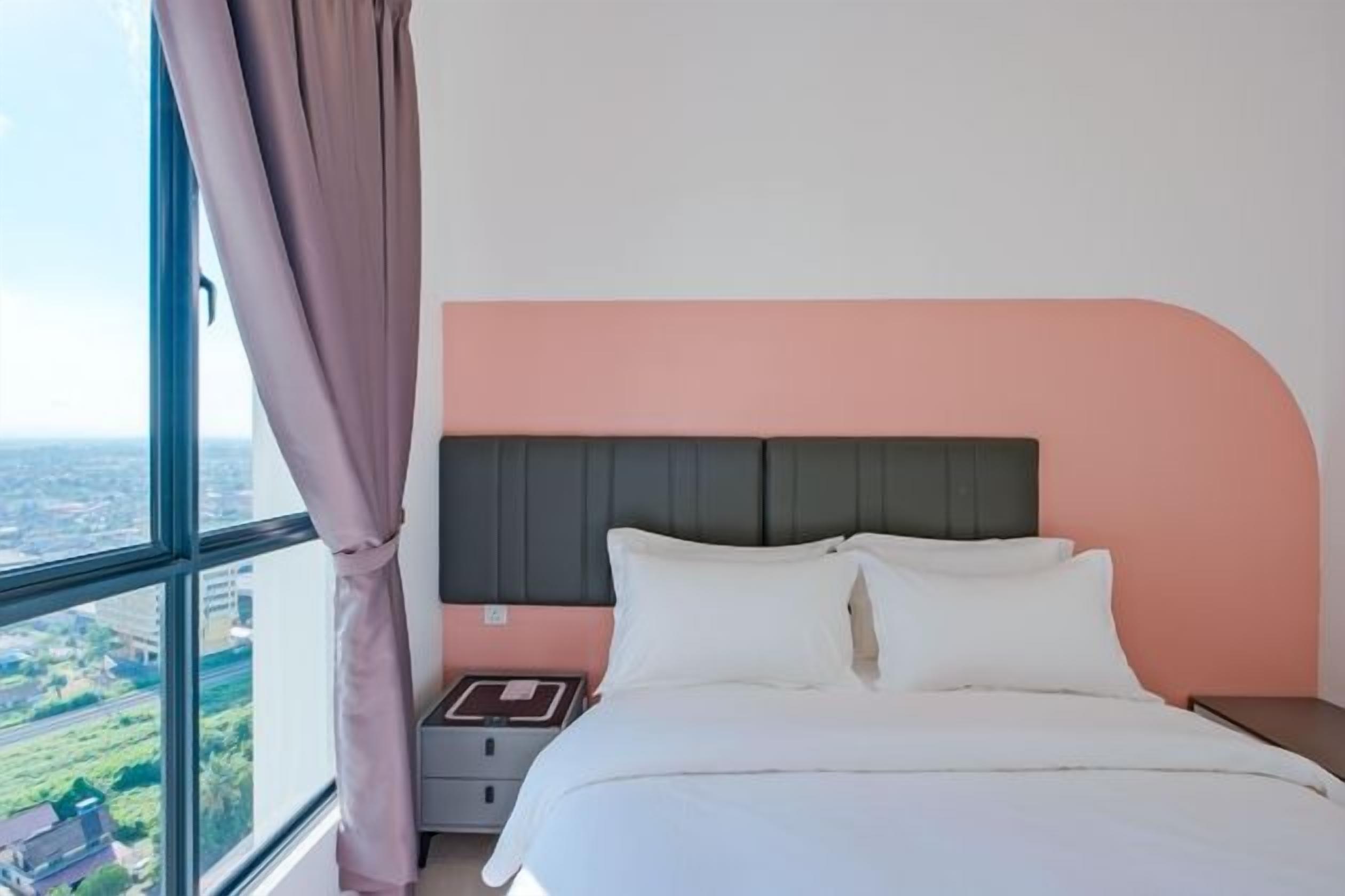 A bedroom with a bed, nightstand, and a window with curtains.