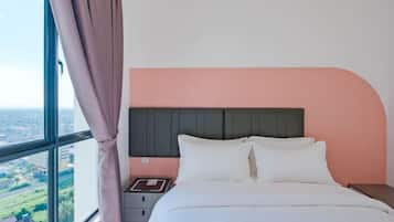 A bedroom with a bed, nightstand, and a window with curtains.