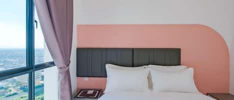 A bedroom with a bed, nightstand, and a window with curtains.