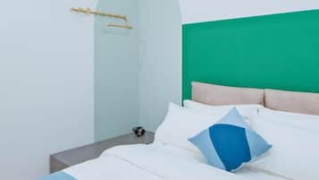A modern bedroom with a green headboard, white bedding, and a small bedside table with a lamp.