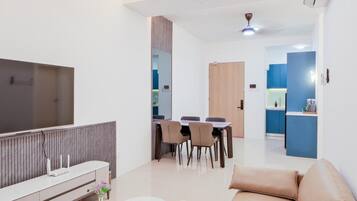 Una sala de estar moderna con un sofá, un televisor, un comedor y una cocina al fondo.