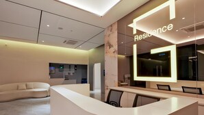 A modern reception area with a curved white counter, a seating area with a sofa, and a large illuminated sign reading 'Residence'. - G Residence Sky Suite (Alor Setar)