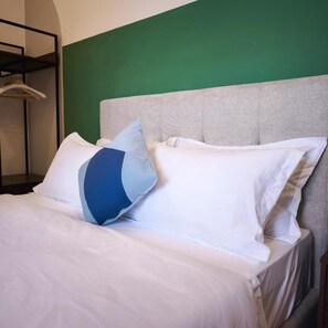 A bed with white bedding and two pillows, one with a blue and white pattern, in a room with a green wall and a grey headboard. - G Residence Sky Suite (Alor Setar)