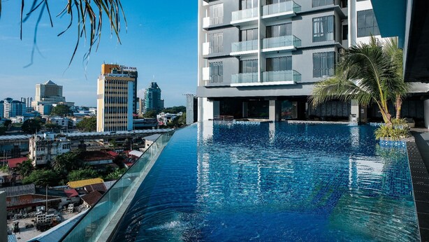 A modern building with a rooftop infinity pool overlooking a cityscape. - G Residence Sky Suite (Alor Setar)
