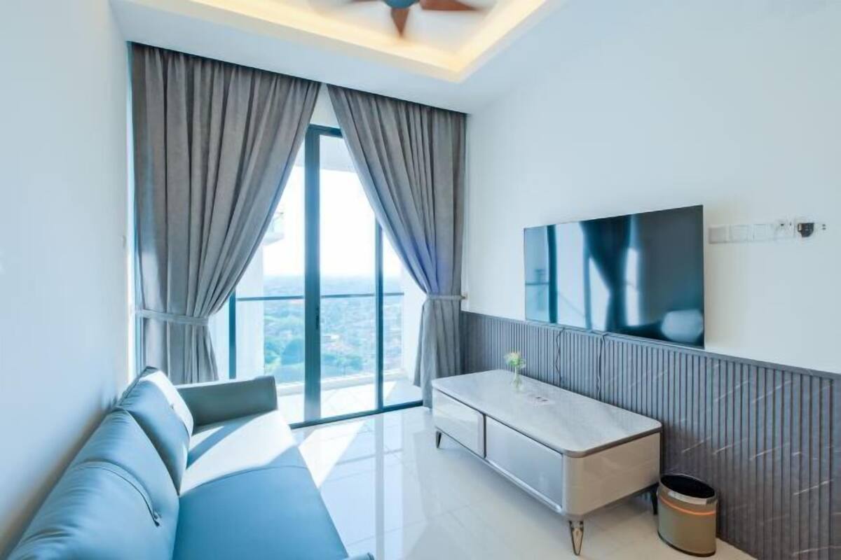 A modern hotel room with a large window, a sofa, a TV, and a small table.