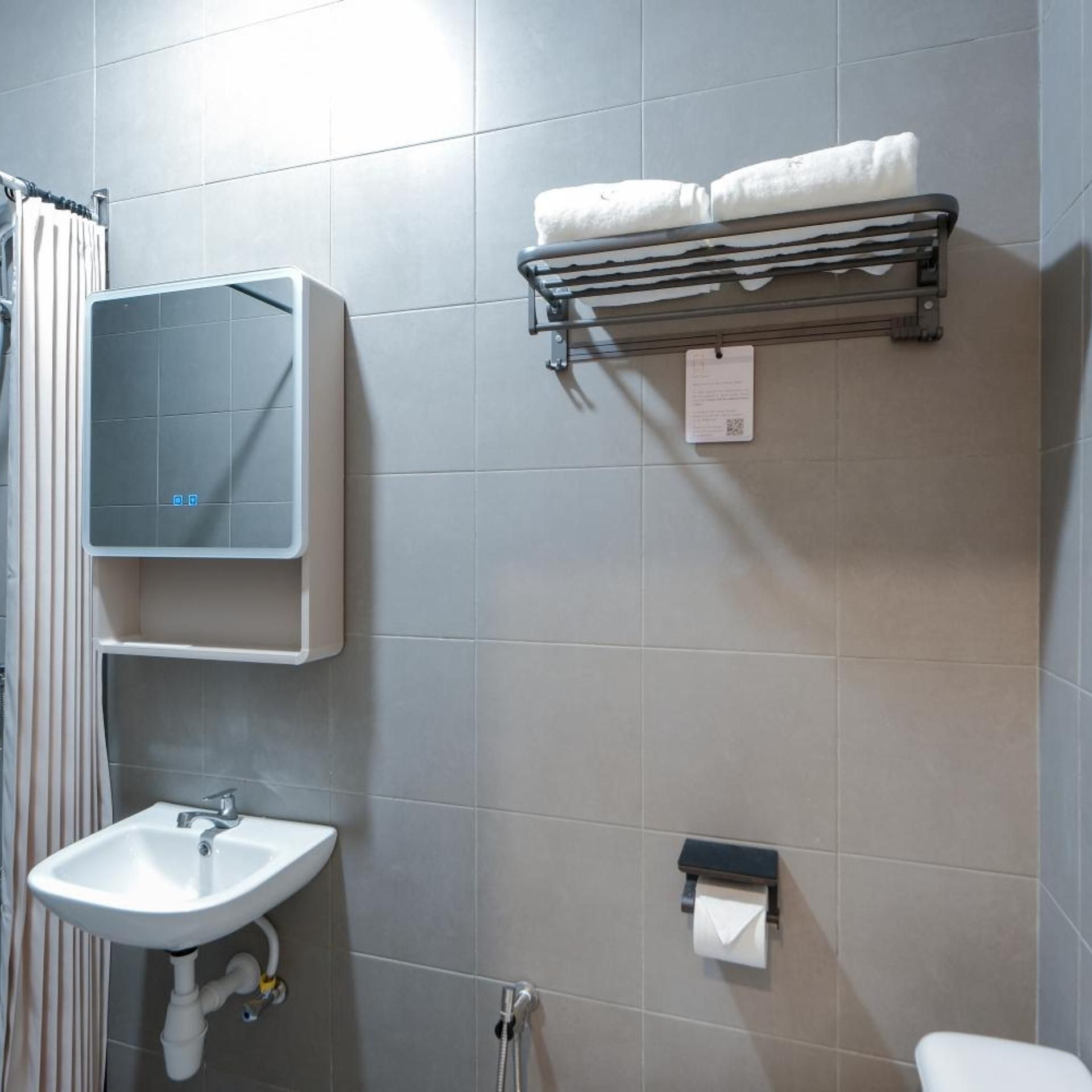 A bathroom with a sink, mirror, towel rack, and toilet paper holder.