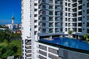 A high-rise building with a rooftop swimming pool and a view of a tower in the background. - G Residence Sky Suite (Alor Setar)