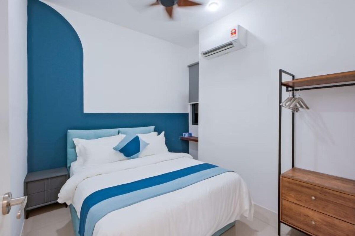 A hotel room with a bed, a wooden dresser, a ceiling fan, and an air conditioning unit.