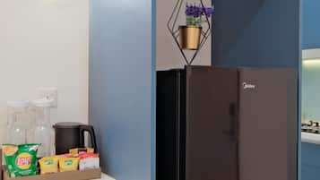Une cuisine avec un réfrigérateur noir, une horloge au mur et une plante suspendue.