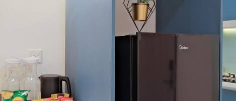 Una cocina con un refrigerador negro, un reloj en la pared y una planta colgante.