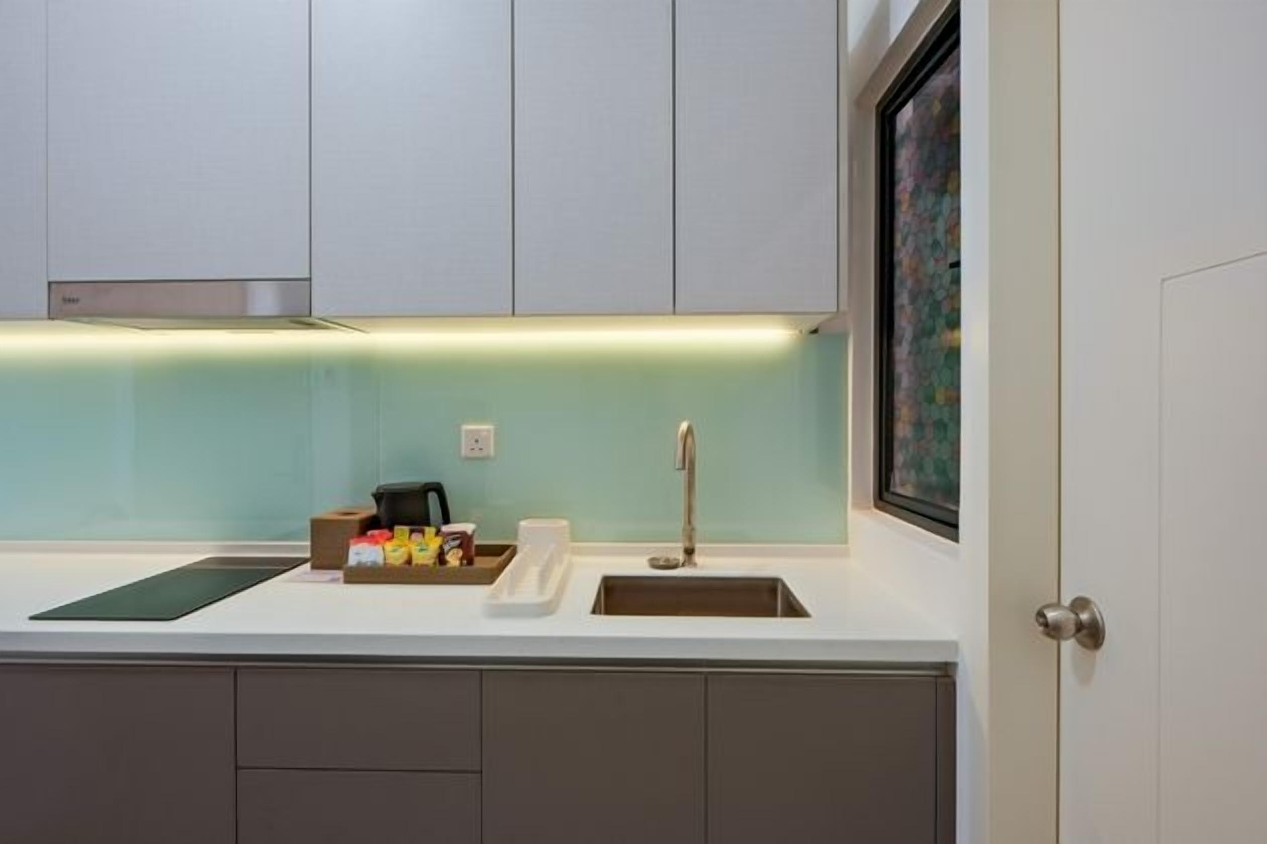 A modern kitchen with a white countertop, stainless steel sink, and a backsplash.