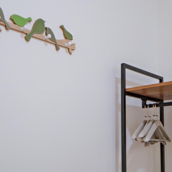 A wall-mounted coat rack with a wooden shelf and a hanging garment. - G Residence Sky Suite (Alor Setar)