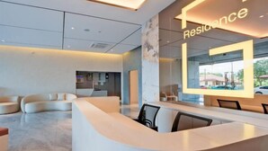 A modern reception area with a curved reception desk, seating area, and a large glass wall with the word "Residence" illuminated. - G Residence Sky Suite (Alor Setar)