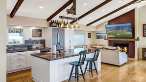 A spacious kitchen with a large island, bar stools, and a fireplace.
