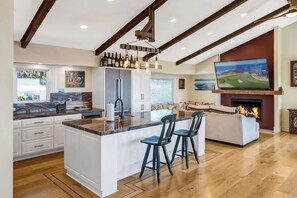 Una cocina amplia con una isla grande, taburetes de bar y una chimenea.