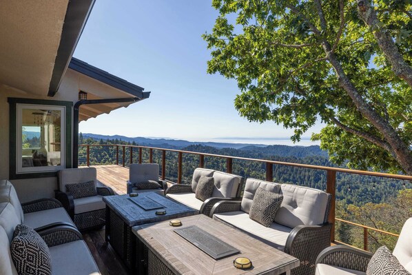 A balcony with outdoor seating, a table, and a view of the mountains.