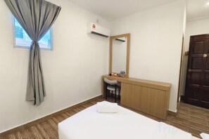 A hotel room with a bed, a small desk, a mirror, and a window with curtains. - Shoreline Guesthouse (Semporna)
