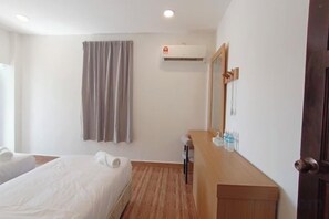 Une chambre d’hôtel avec un lit, une commode en bois, un miroir, un appareil de climatisation et une fenêtre avec des rideaux.