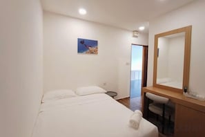 A hotel room with a bed, a bedside table, a mirror, and a painting on the wall. - Shoreline Guesthouse (Semporna)