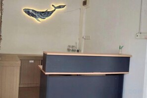 Un comptoir d’accueil surmonté d’un luminaire en forme de baleine.