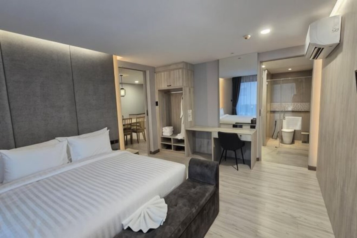 Une chambre d’hôtel avec un grand lit, un bureau, une chaise et une armoire.